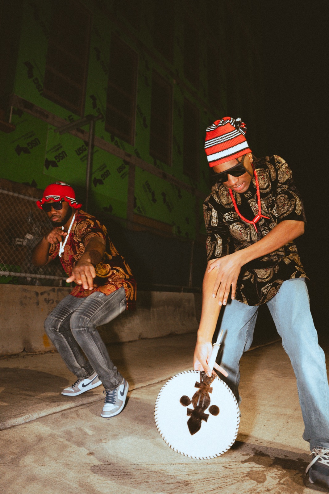 Osa Deraé and a friend dancing in red Igbo caps